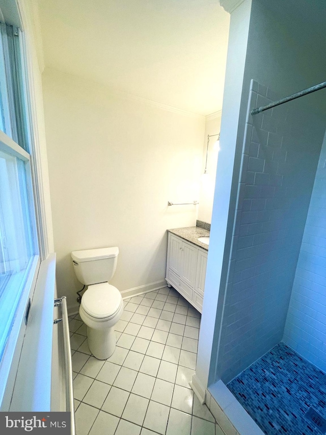 bathroom with tile patterned floors, vanity, a tile shower, toilet, and ornamental molding