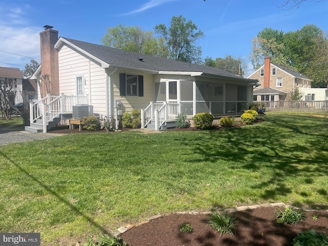 back of house featuring a chimney, fence, a yard, central AC, and a sunroom