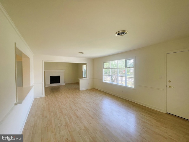 unfurnished living room with visible vents, baseboards, wood finished floors, and a fireplace with raised hearth