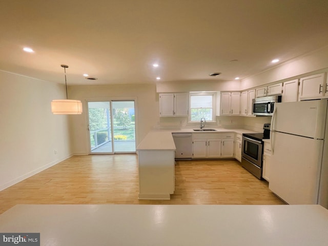 kitchen featuring recessed lighting, light countertops, a sink, light wood-type flooring, and appliances with stainless steel finishes