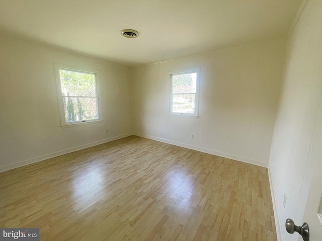 unfurnished room featuring light wood-style flooring, visible vents, and baseboards