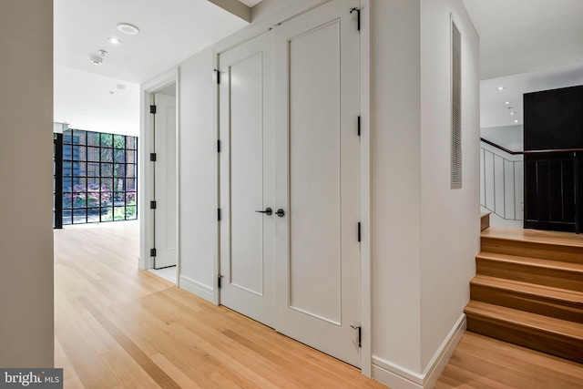 hallway featuring baseboards, recessed lighting, light wood finished floors, and stairway