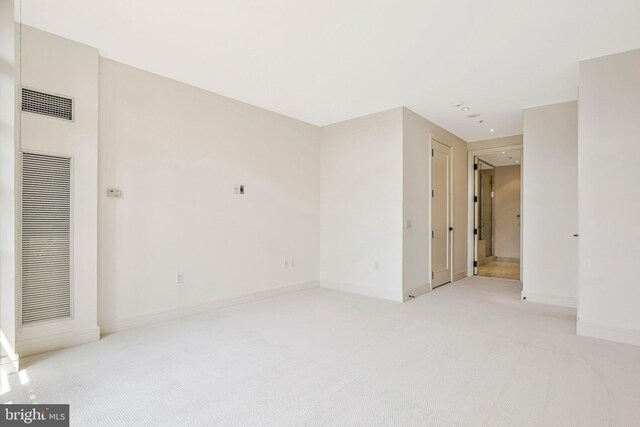 spare room featuring light colored carpet, recessed lighting, baseboards, and a heating unit