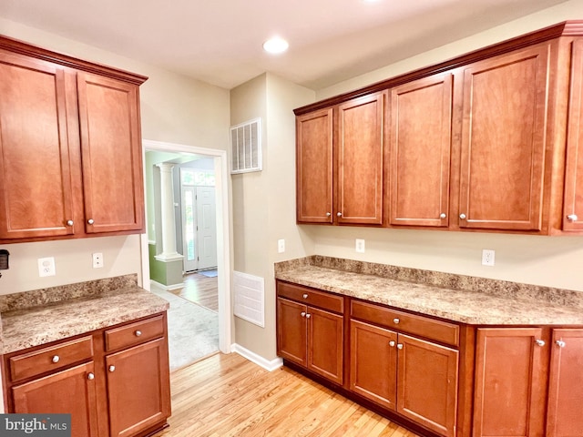 388 Wood Landing Rd, Fredericksburg, VA 22405 - kitchen featuring visible vents, brown cabinetry, decorative columns, light countertops, and light wood finished floors