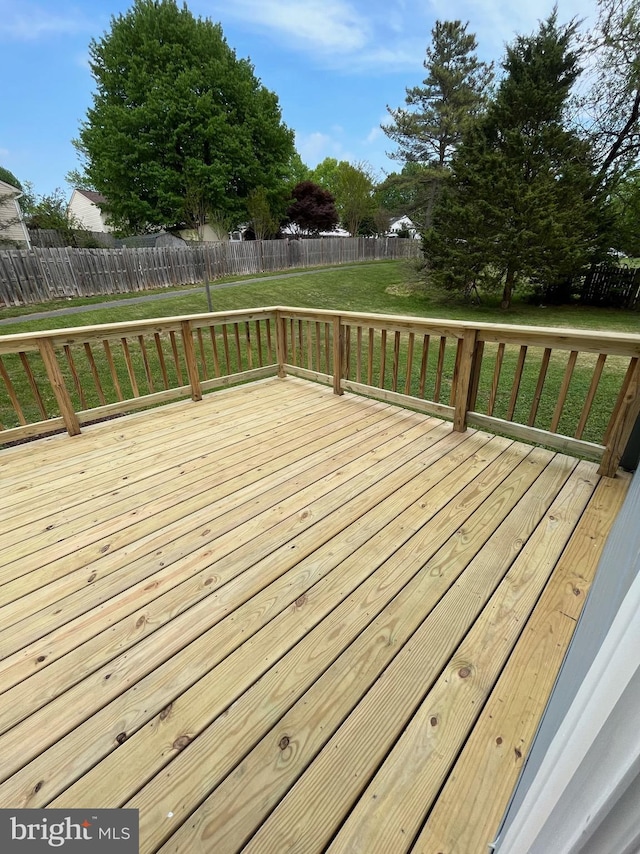 wooden terrace with a fenced backyard and a lawn