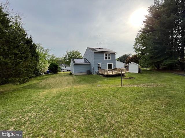 rear view of property featuring a lawn, an outbuilding, and a wooden deck