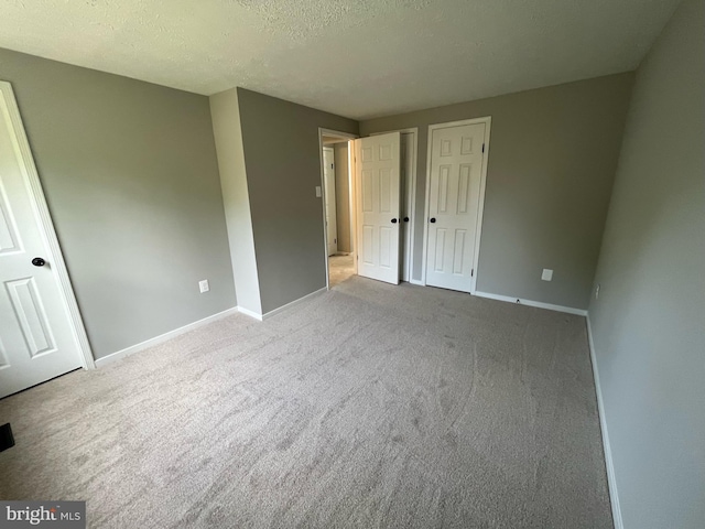 unfurnished bedroom featuring baseboards, carpet flooring, and a textured ceiling