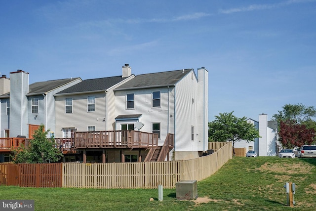 rear view of house with a lawn, a deck, and fence