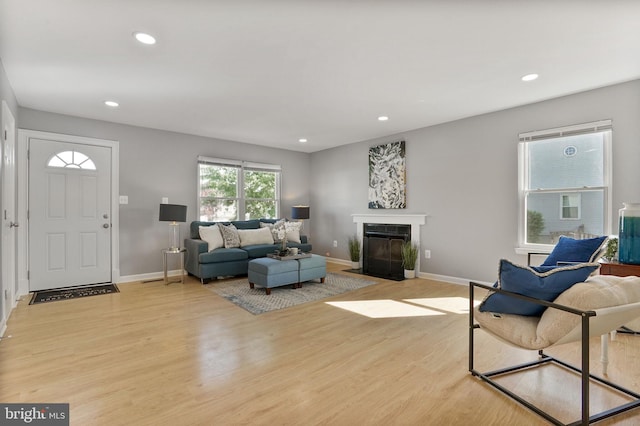 living room with a fireplace with flush hearth, baseboards, recessed lighting, and light wood-type flooring