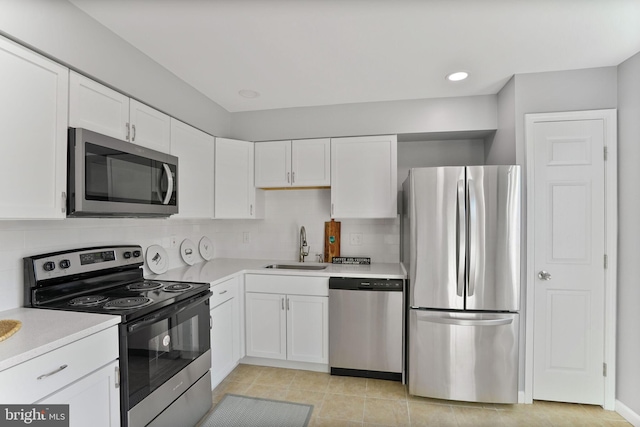 kitchen featuring decorative backsplash, appliances with stainless steel finishes, a sink, light countertops, and white cabinets
