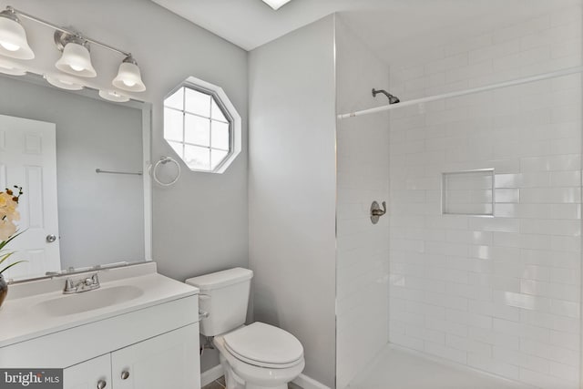 full bathroom featuring vanity, toilet, and tiled shower