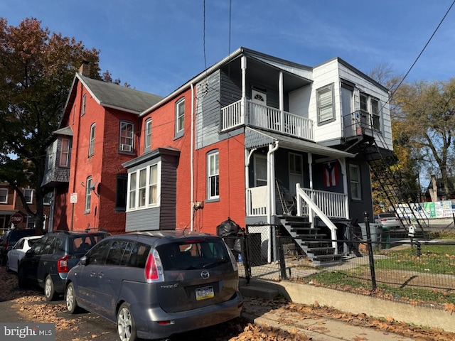 view of front of home with a porch, a balcony, and fence private yard