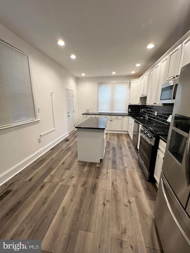 6232 N 10th St, Philadelphia, PA 19141 - kitchen with a center island, dark countertops, stainless steel appliances, white cabinetry, and dark wood-style flooring