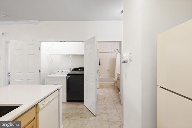 kitchen featuring crown molding, white appliances, light countertops, light tile patterned floors, and washing machine and dryer