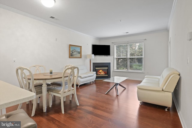 dining space featuring crown molding, a fireplace with flush hearth, visible vents, and dark wood-style floors