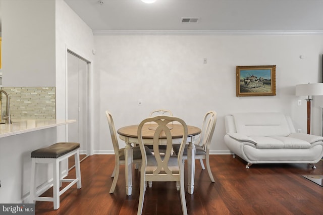 dining room featuring baseboards, visible vents, ornamental molding, and wood finished floors