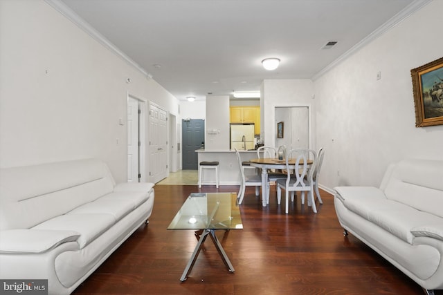 living room with visible vents, ornamental molding, baseboards, and wood finished floors