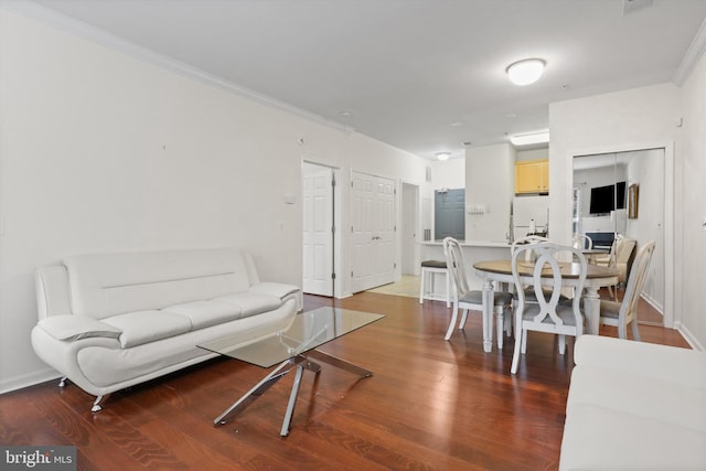 living area featuring baseboards, ornamental molding, and wood finished floors