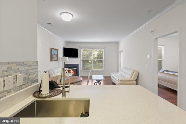 interior space featuring visible vents, ornamental molding, dark wood-style flooring, and a glass covered fireplace