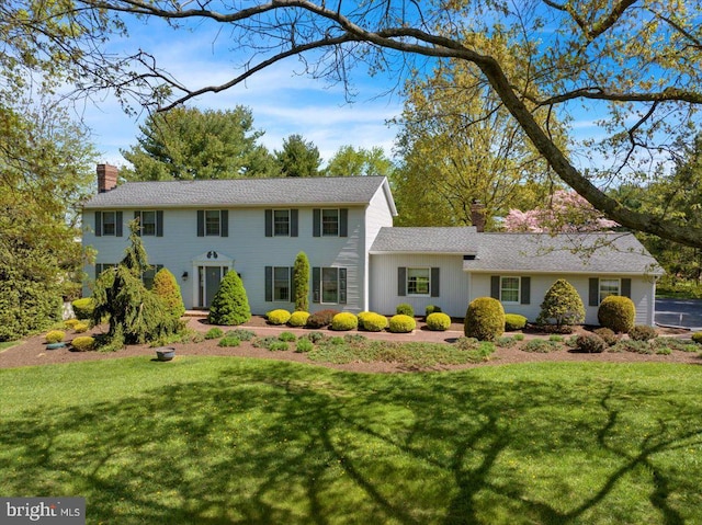 colonial inspired home featuring a front yard and a chimney