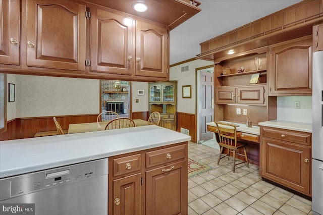 kitchen featuring wooden walls, wainscoting, built in study area, dishwasher, and light countertops