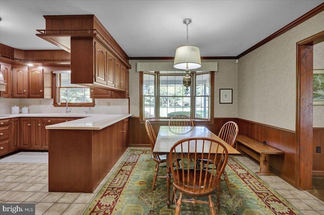 dining area featuring crown molding, light tile patterned floors, wainscoting, and wood walls