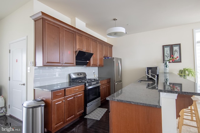 kitchen with dark wood-style flooring, a breakfast bar area, stainless steel appliances, a peninsula, and decorative backsplash