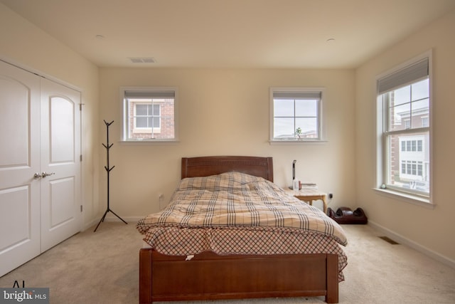 bedroom featuring baseboards, visible vents, and light carpet
