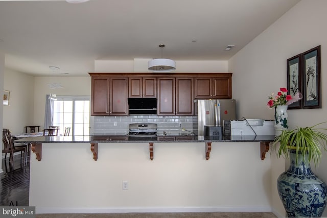 kitchen featuring dark stone counters, stainless steel appliances, and a kitchen bar