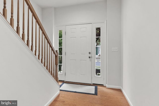 entryway with stairs, baseboards, and wood finished floors