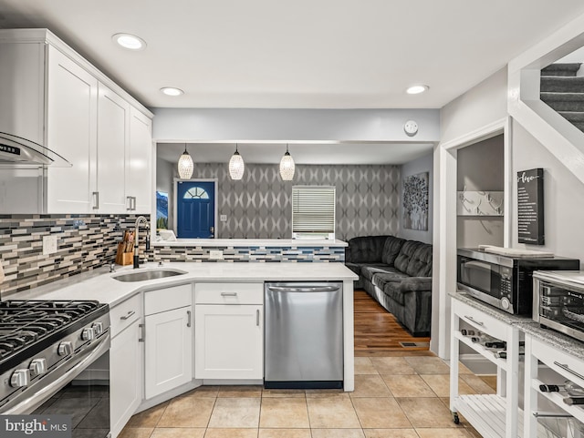 1016 Euclid Ave, Wilmington, DE 19809 - kitchen featuring appliances with stainless steel finishes, a sink, wall chimney exhaust hood, white cabinetry, and wallpapered walls
