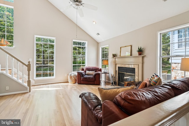 living area featuring wood finished floors, ceiling fan, a premium fireplace, visible vents, and high vaulted ceiling