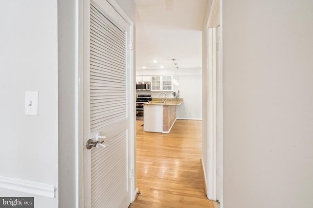 hall featuring recessed lighting, light wood-style flooring, and a sink