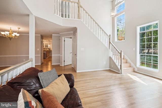 living room with wood finished floors, a chandelier, baseboards, stairway, and a towering ceiling