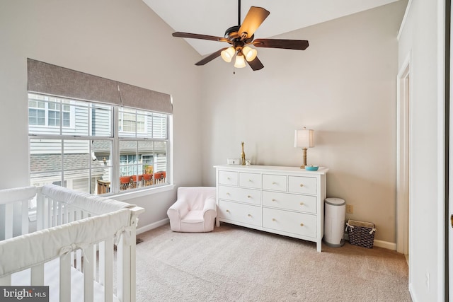 bedroom with baseboards, a nursery area, light carpet, and ceiling fan