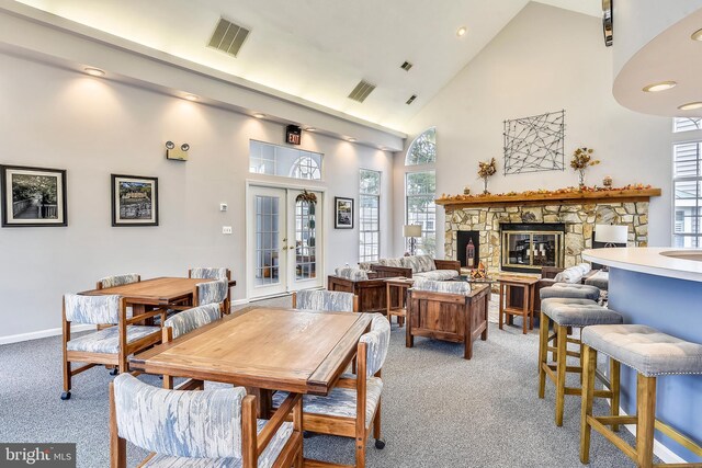 dining room featuring visible vents, plenty of natural light, high vaulted ceiling, and light carpet
