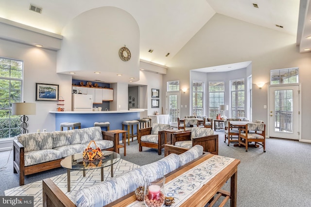 living area featuring visible vents, a healthy amount of sunlight, carpet, and high vaulted ceiling