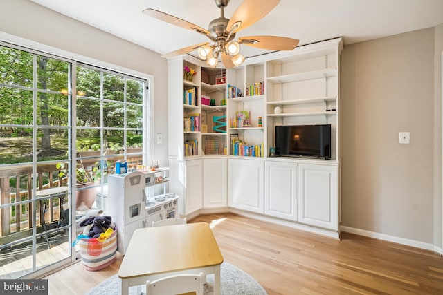 living area featuring baseboards, a ceiling fan, and light wood-style flooring