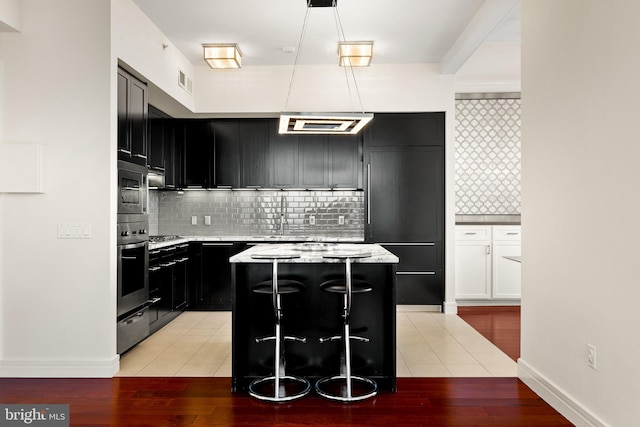1414 S Penn Sq Unit 34B, Philadelphia, PA 19102 - kitchen featuring tasteful backsplash, oven, a kitchen island, hanging light fixtures, and dark cabinets