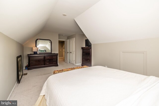 bedroom featuring lofted ceiling and light carpet