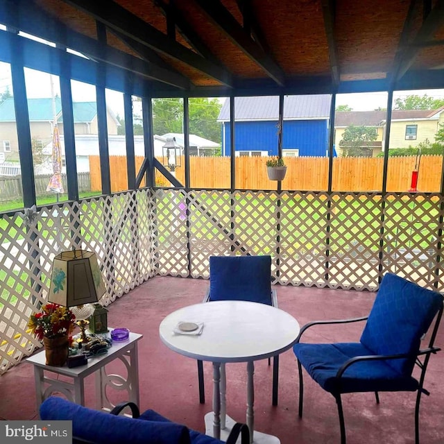 sunroom featuring a healthy amount of sunlight, outdoor dining area, and beamed ceiling