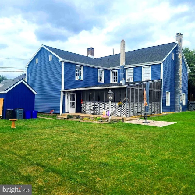 rear view of house featuring a lawn, a chimney, a patio area, and a sunroom