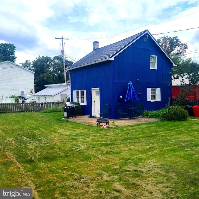 rear view of house featuring metal roof, fence, a yard, and a patio area
