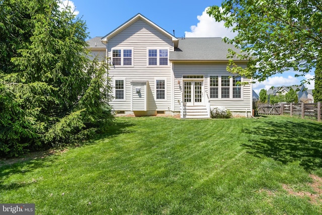 back of house with entry steps, fence, and a yard