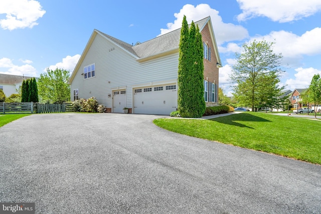 view of home's exterior with fence, a shingled roof, an attached garage, a lawn, and driveway