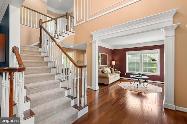 stairs with crown molding, baseboards, decorative columns, and hardwood / wood-style flooring