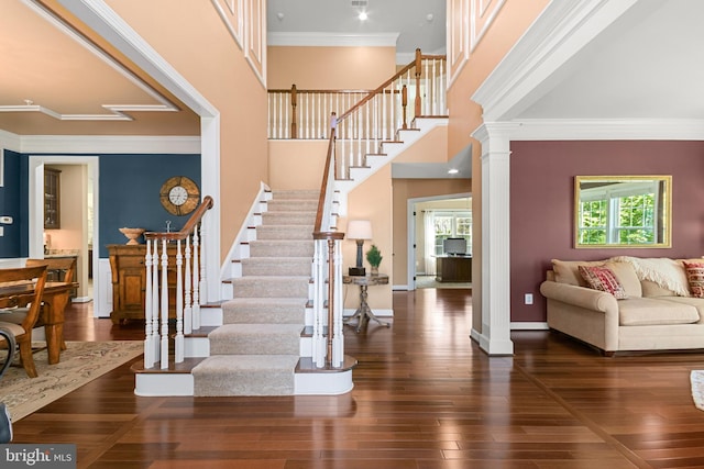 entryway with crown molding, stairs, hardwood / wood-style flooring, and decorative columns