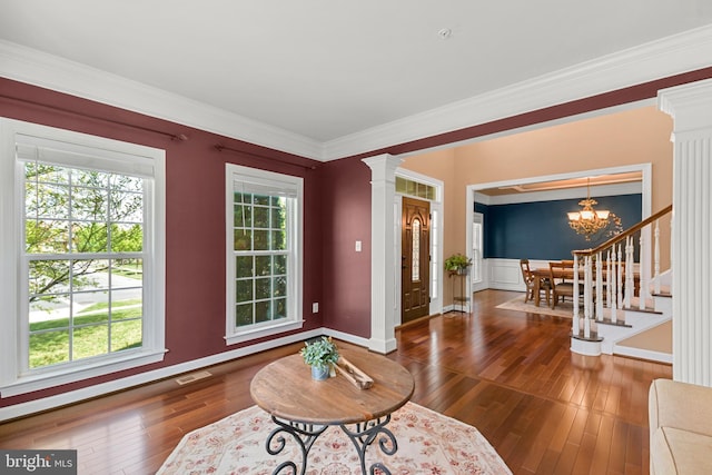 living area featuring crown molding, a chandelier, baseboards, visible vents, and hardwood / wood-style flooring