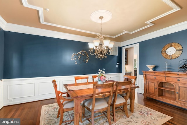 dining area with wainscoting, dark wood finished floors, a chandelier, ornamental molding, and a decorative wall