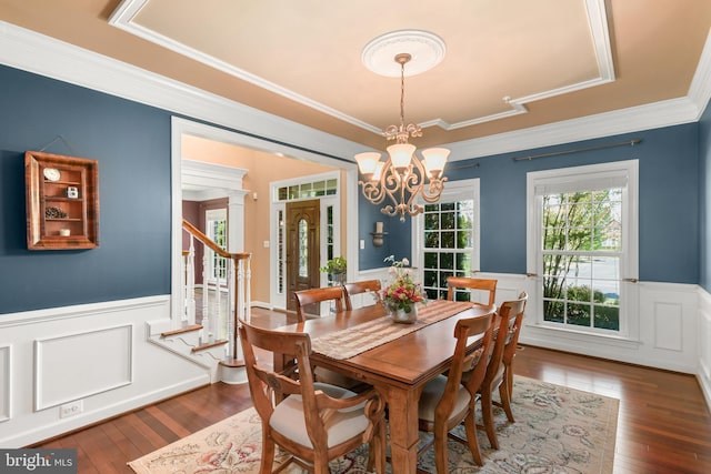 dining area featuring crown molding, a wainscoted wall, an inviting chandelier, and hardwood / wood-style floors